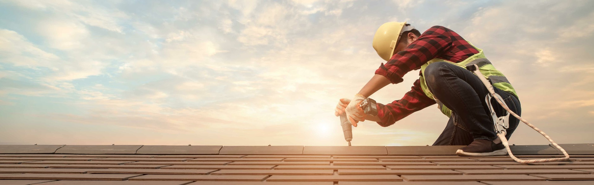 Dachdecker mit speziellen Arbeitsschutzhandschuhen arbeitet auf dem Dach