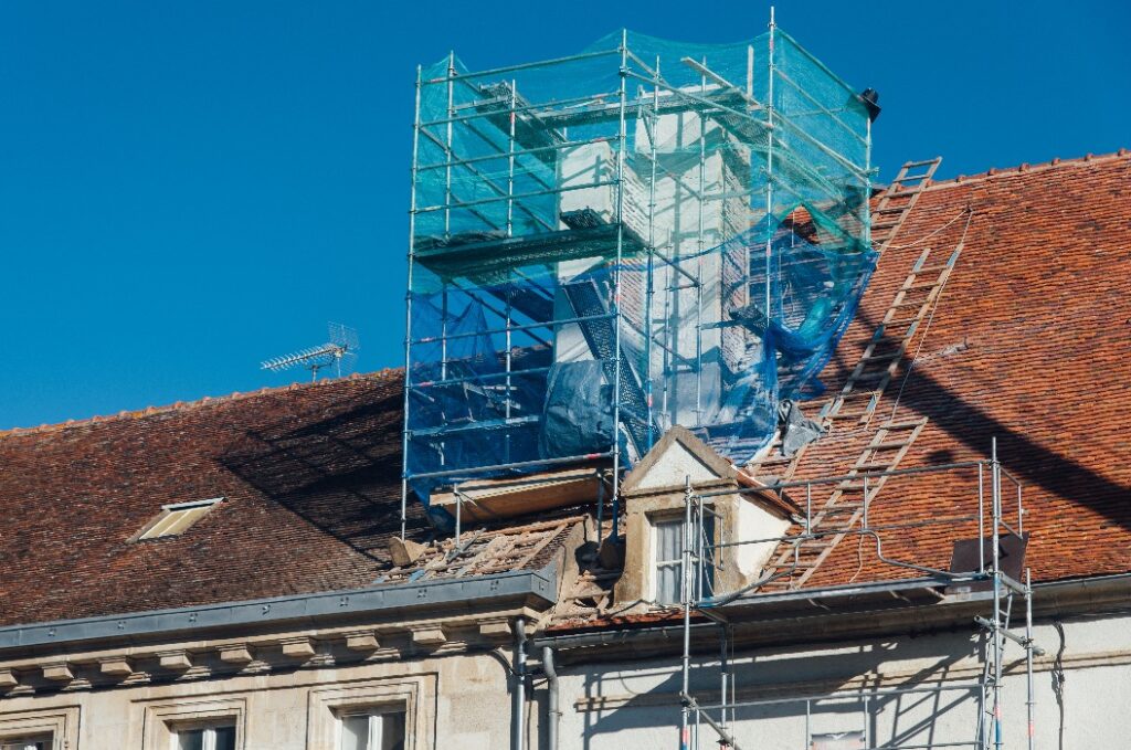 Die Restaurierung eines alten Kamins auf einem alten Dach eines alten historischen Gebäudes. Ein Gerüst an einem Schornstein. Renovierung eines Kamins